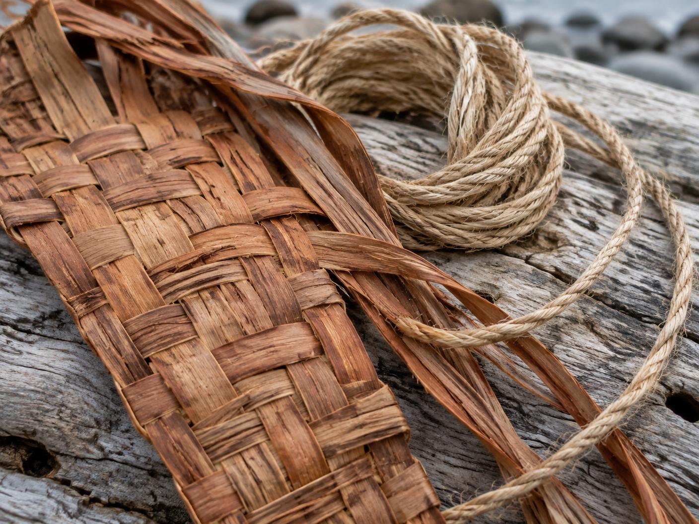 Close detail of woven cedar bark and natural fibre cordage resting on driftwood